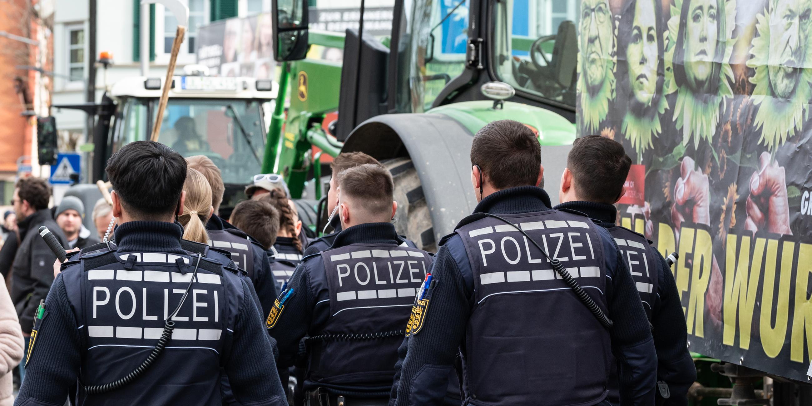  Polizisten gehen während einer Demonstration vor Beginn des politischen Aschermittwochs der baden-württembergischen Grünen vor der Stadthalle in Biberach.