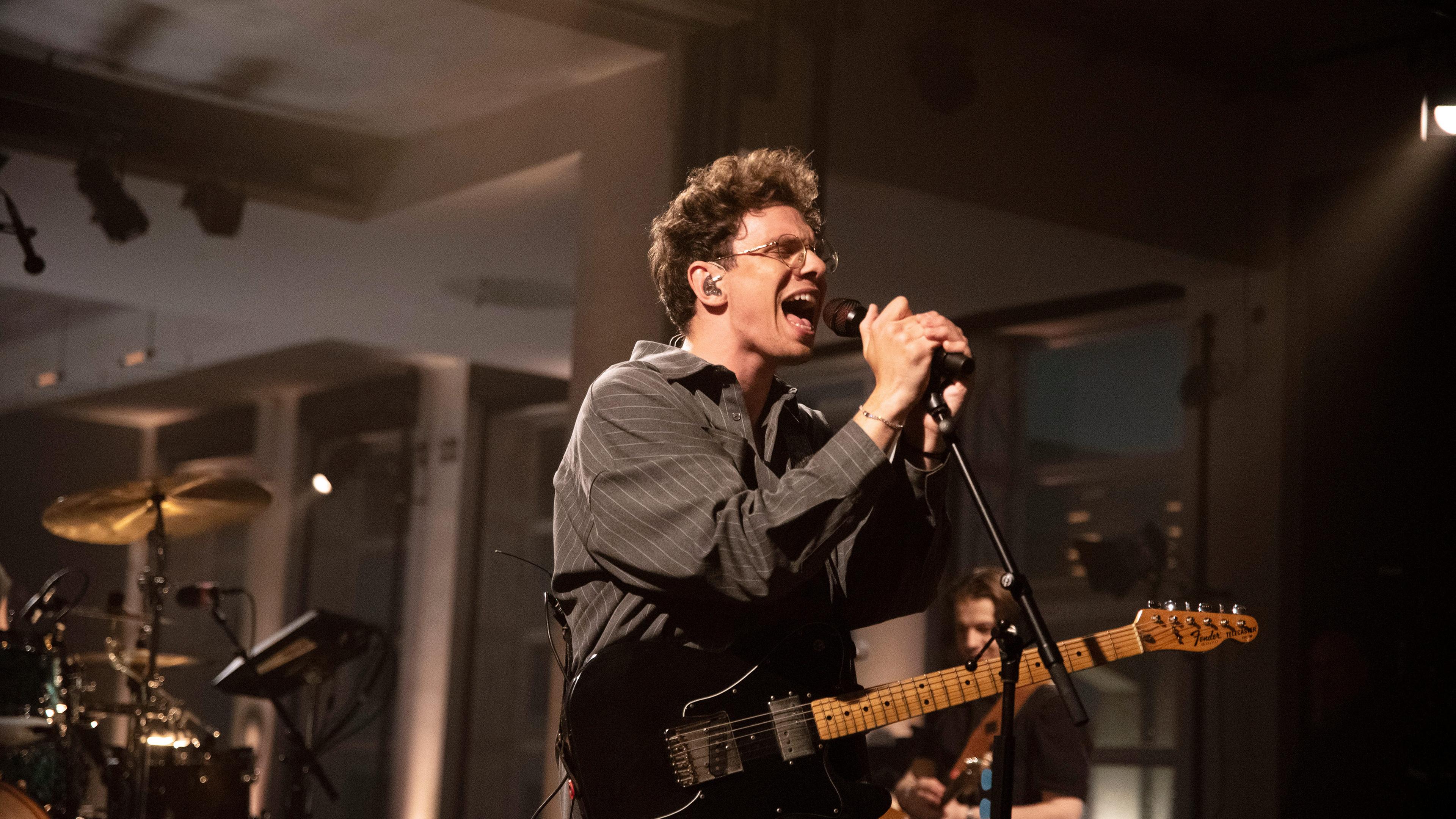 Der Sänger Kamrad singt auf einer Bühne ins Mikro.