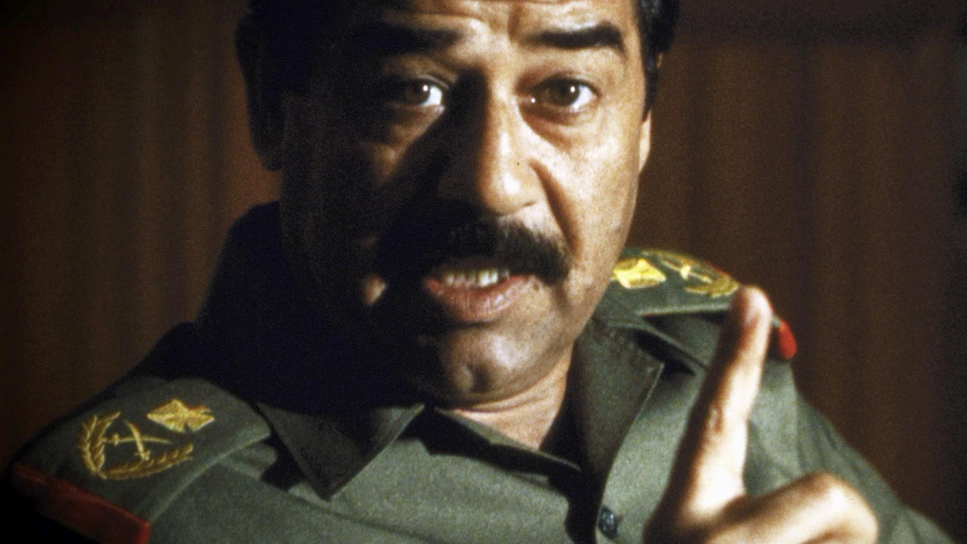 "Bauplan des Bösen: Saddam Hussein": Ein Mann in Uniform schaut mit offenem Mund und erhobenem Zeigefinger in die Kamera. Es scheint, als würde er reden.