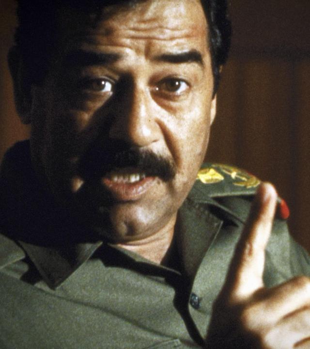 "Bauplan des Bösen: Saddam Hussein": Ein Mann in Uniform schaut mit offenem Mund und erhobenem Zeigefinger in die Kamera. Es scheint, als würde er reden.