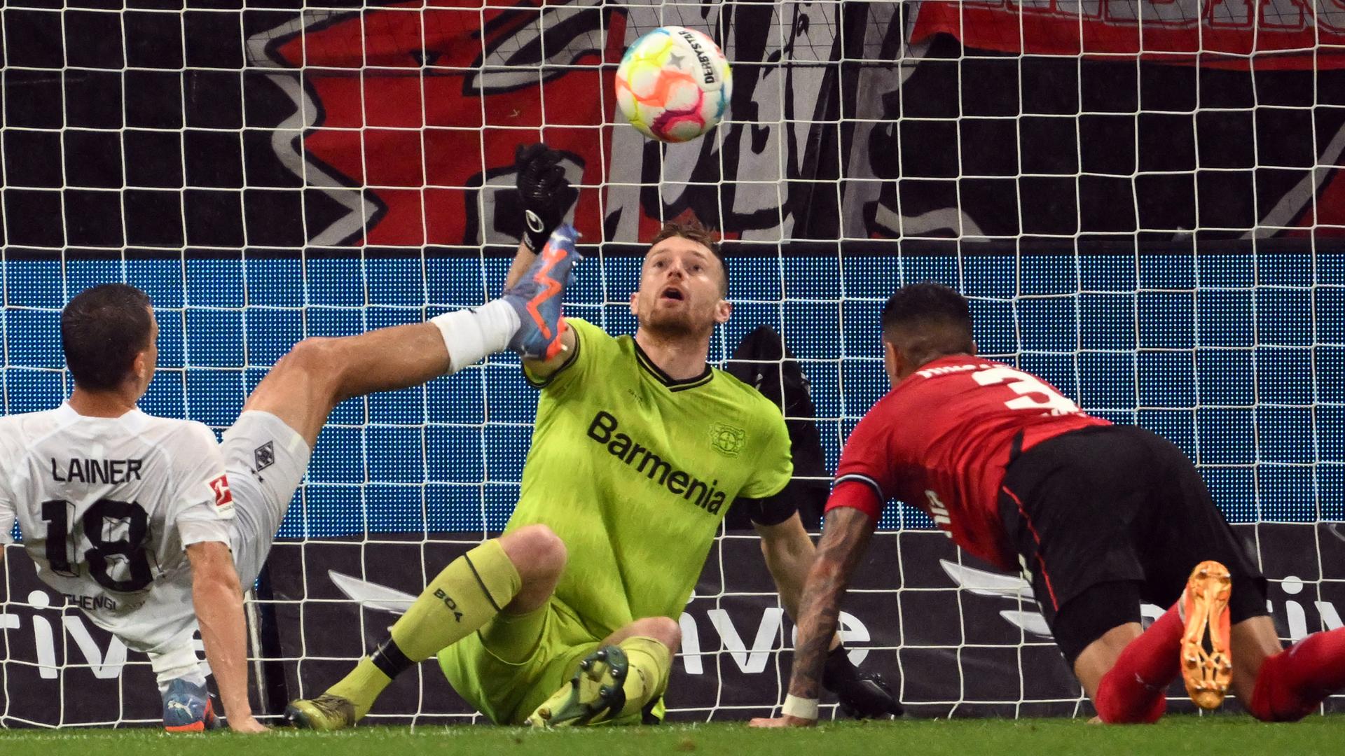 Leverkusens Torwart Lukas Hradecky (M) und Mönchengladbachs Stefan Lainer kämpfen um den Ball.