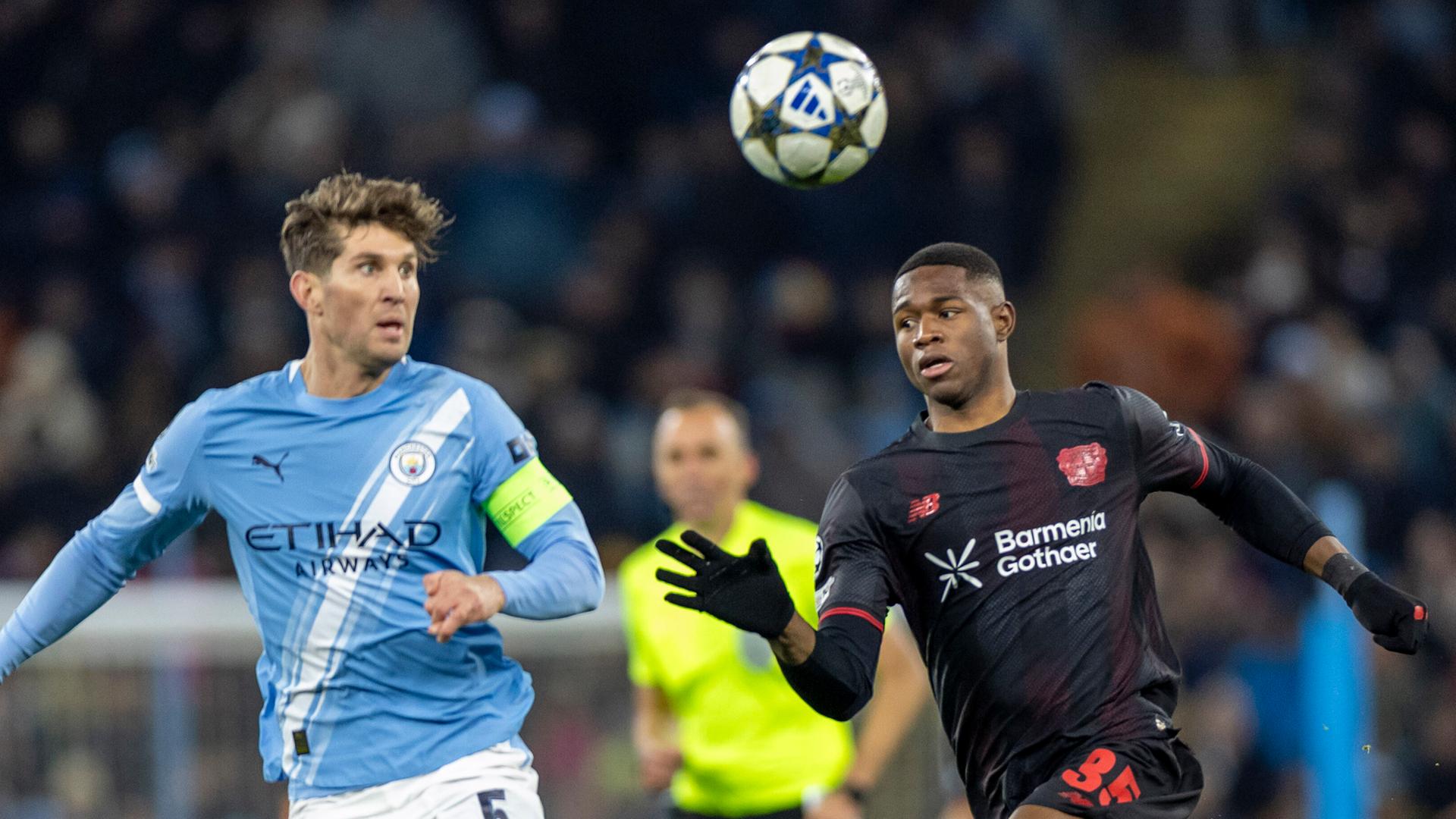 John Stones (Manchester City) und Christian Kofane (Bayer Leverkusen) kämpfen. 