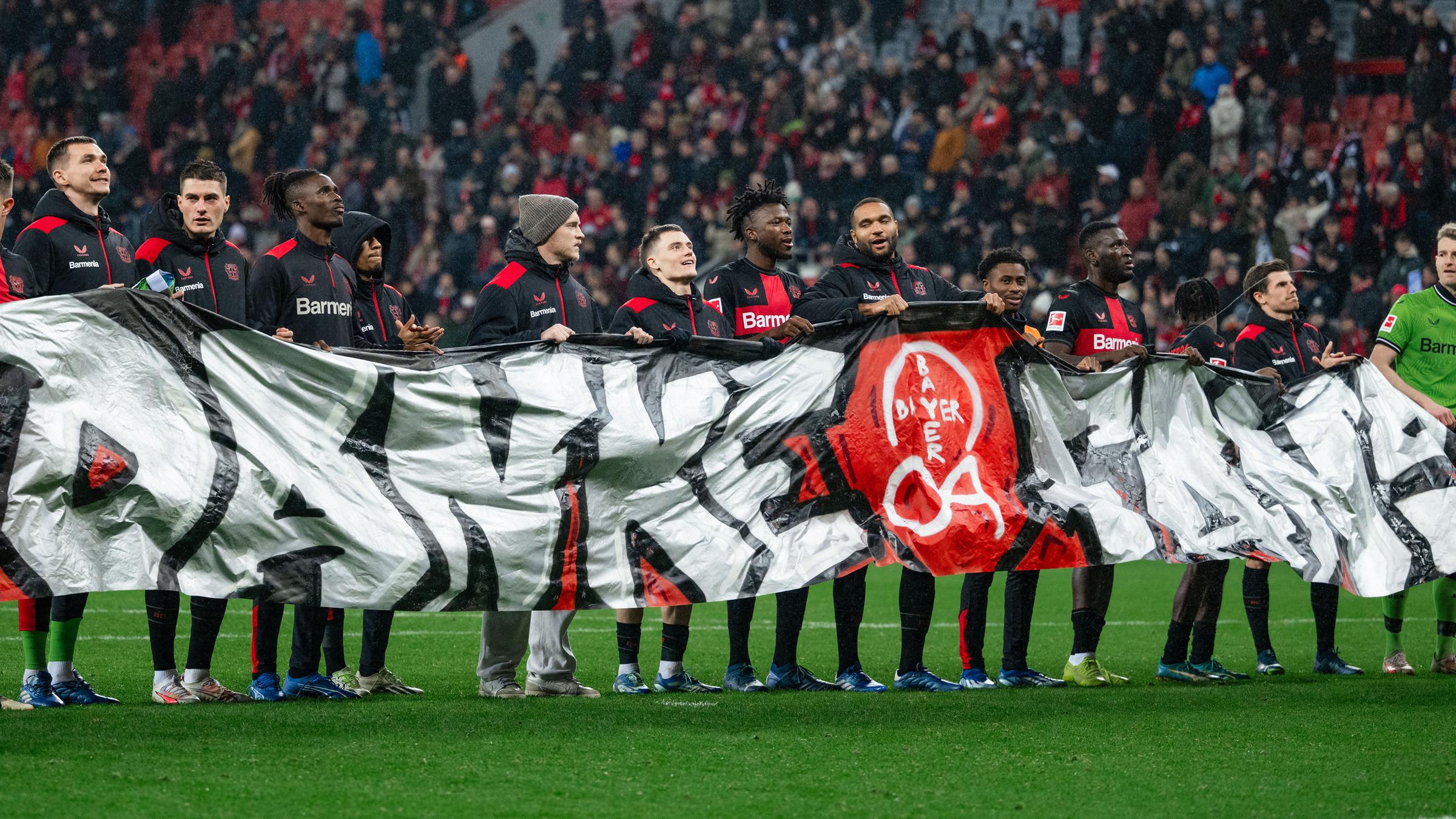 Die Leverkusener Spieler halten nach der Partie ein Banner mit der Aufschrift "Danke Fans" in den Händen am 20.12.2023.