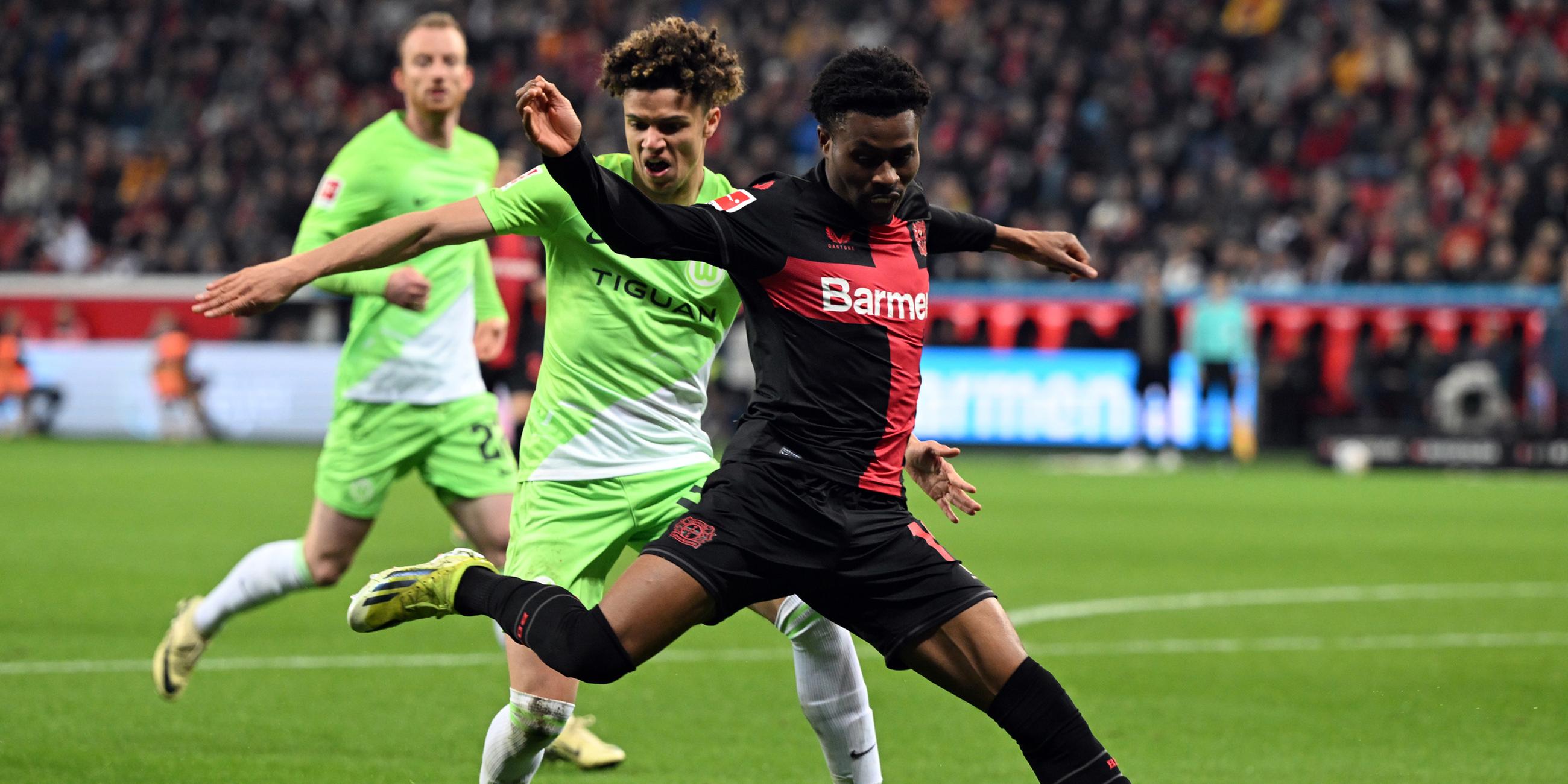 Leverkusens Nathan Tella (r) und Wolfsburgs Kevin Paredes kämpfen um den Ball.