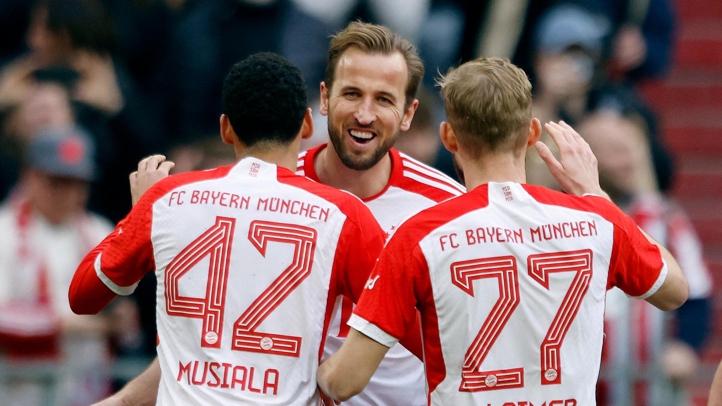 Münchens Harry Kane jubelt mit Jamal Musiala und Konrad Laimer beim Spiel gegen Mainz am 09.03.2024.
