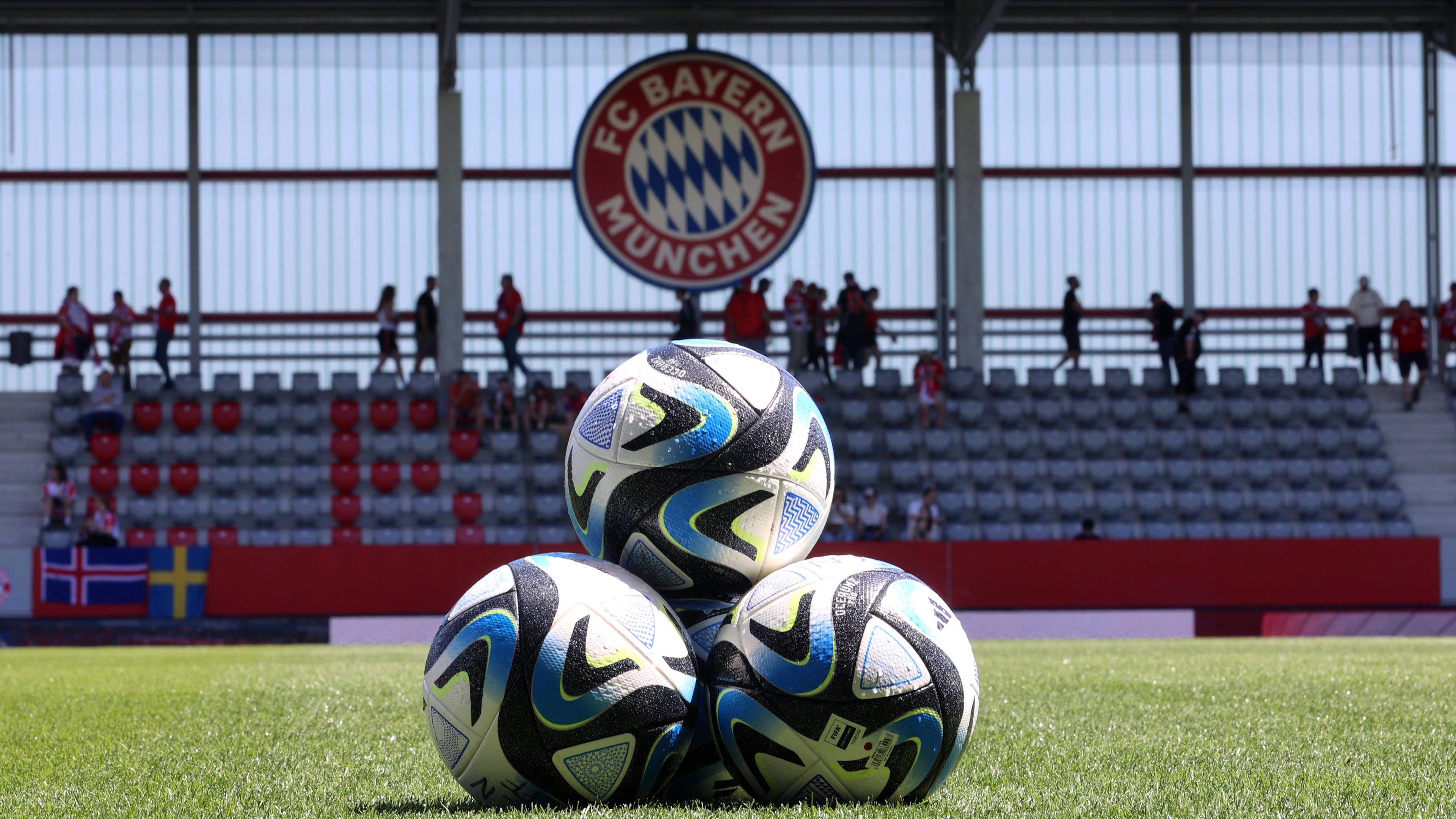 Drei Bälle aufeinander aufgestapelt, im Hintergrund das Logo des FC Bayern