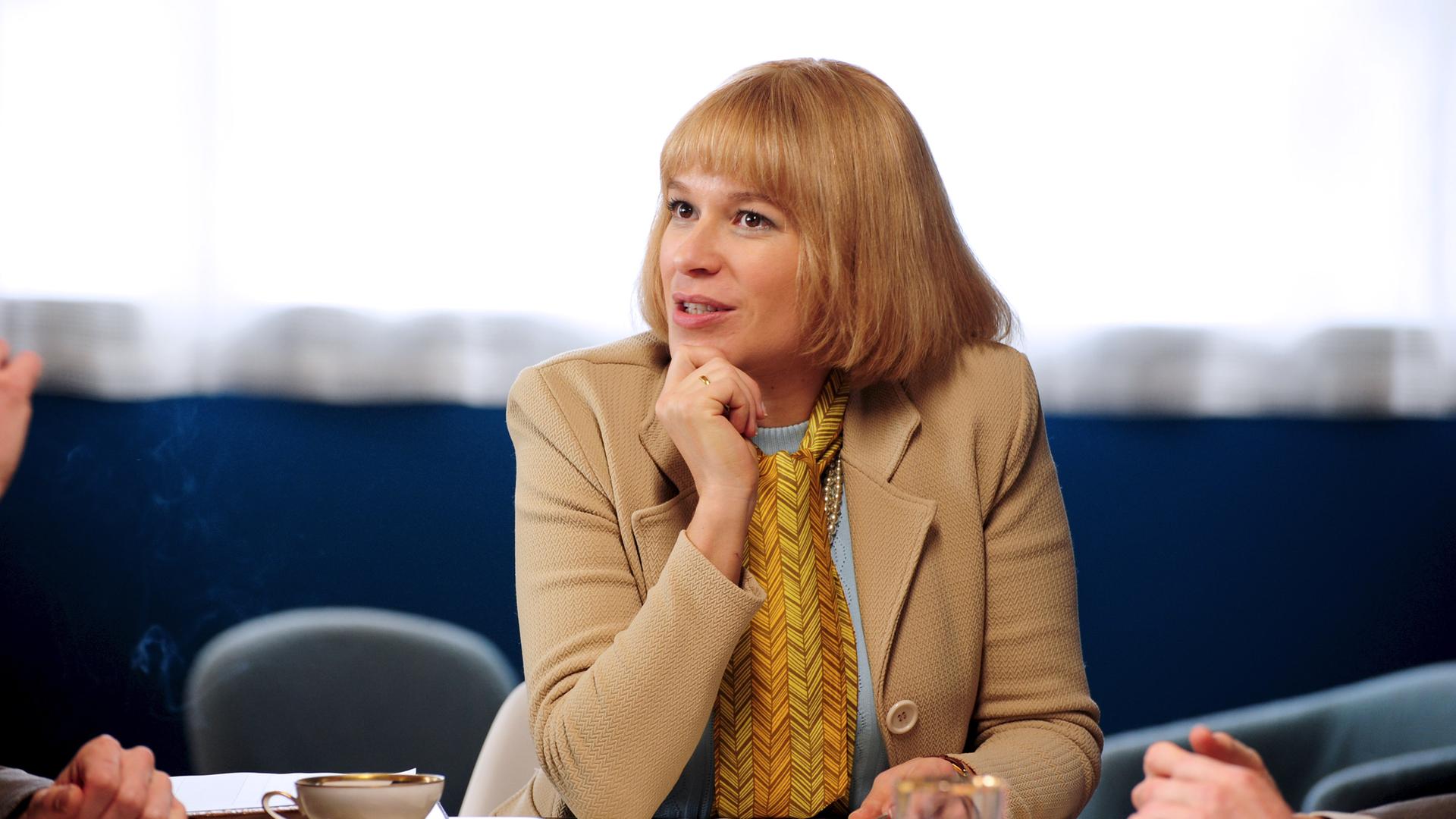 Beate (Franka Potente) hat ihre Firma vergrößert und hält eine Mitarbeiterbesprechung ab.