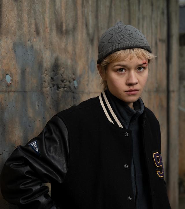 Charlie (Lea Drinda) steht vor einer grauen Steinwand