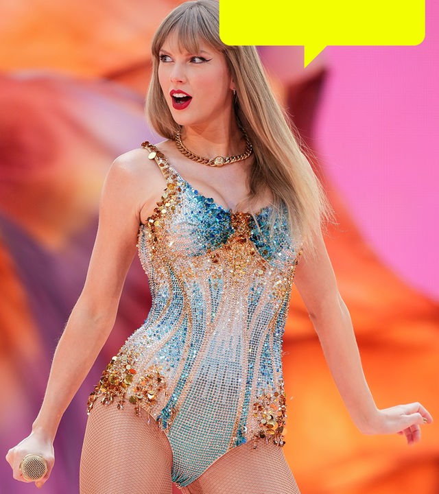 Taylor Swift steht auf der Bühne und trägt ein glitzerndes, buntes Kleid und eine auffällige Halskette vor unscharfem rosa-orangfarbenem Hintergrund.