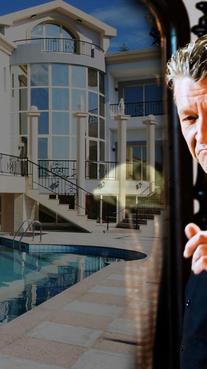 Erwin Pelzig steht schick gekleidet vor einem Spiegel und erhebt den Zeigefinger. Im Spiegel ist eine teure Villa mit Pool zu sehen.