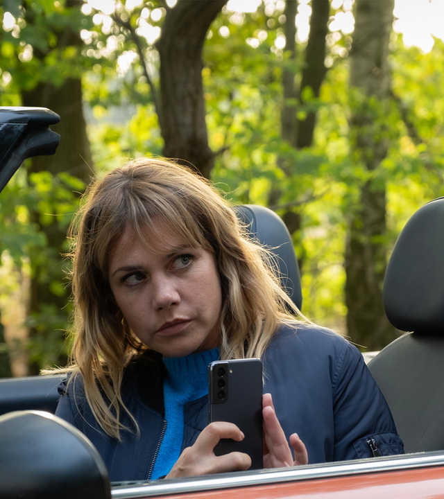 „Neuer Wind im Alten Land – Beke wirbelt auf“: Beke (Felicitas Woll) sitzt in ihrem offenen Cabrio und macht aus dem Auto heraus ein Bild mit ihrem Handy.