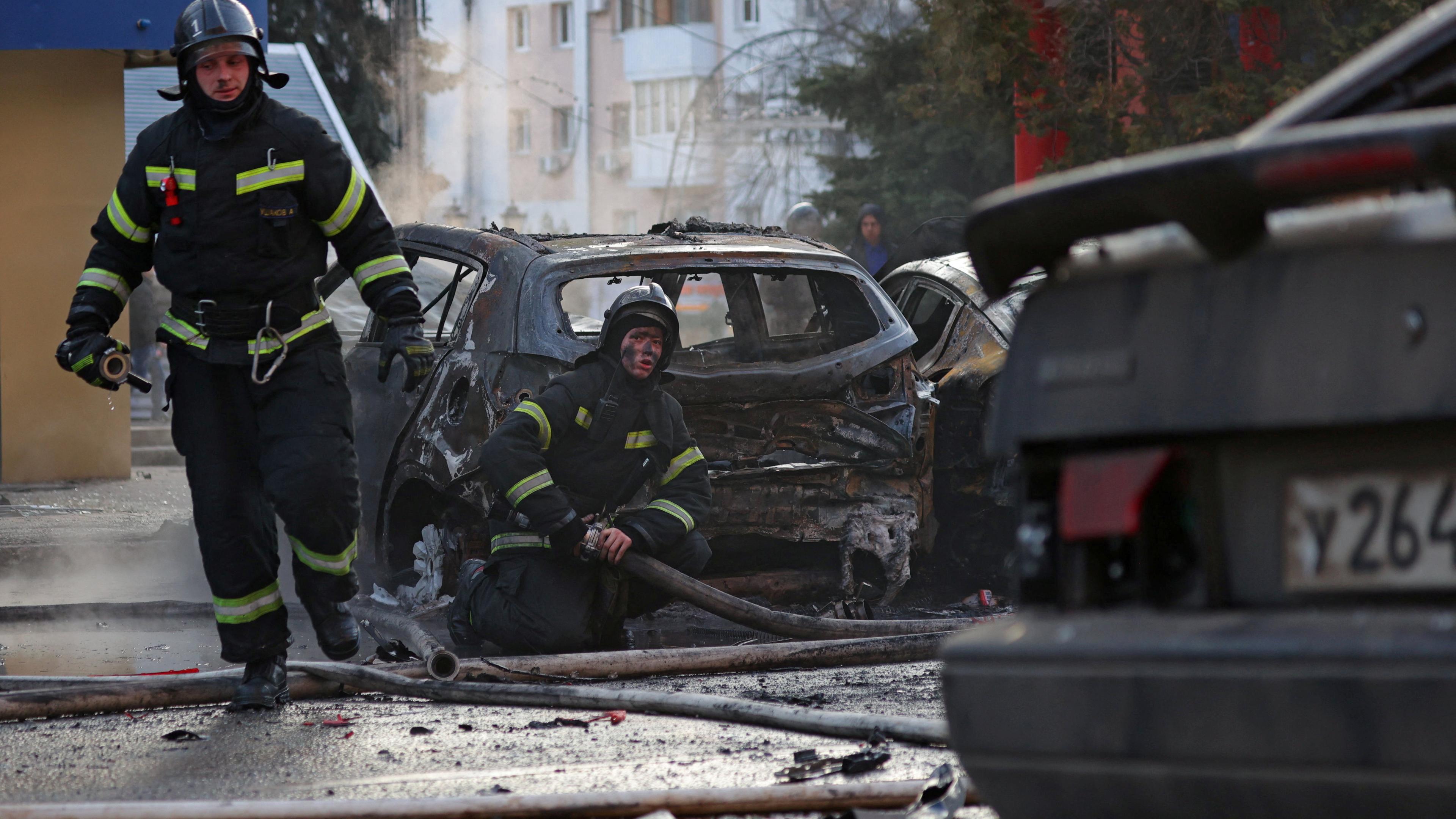 Feuerwehrmänner zwischen Autowracks nach einem Angriff im russischen Belgorod.