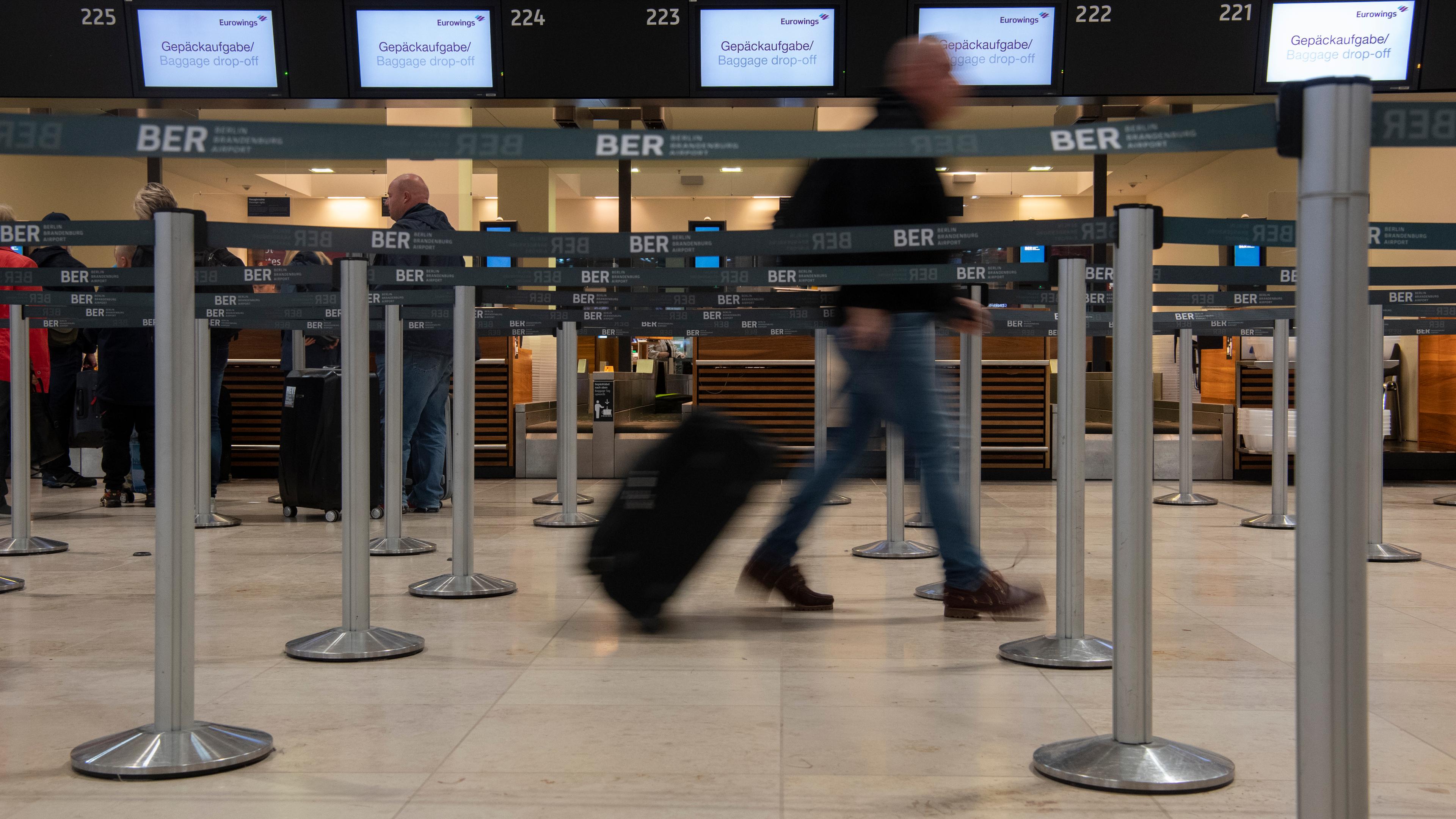 Berlin: Ein Reisender geht mit einem Koffer zu einem Check-in-Schalter von Eurowings.