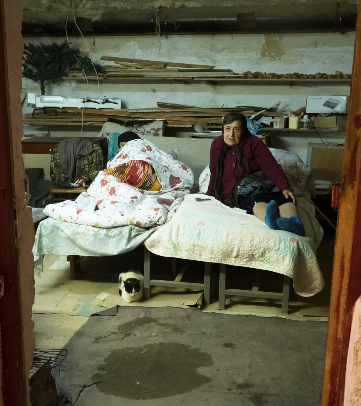 Frauen liegen in einem Bett in einem Schutzraum.
