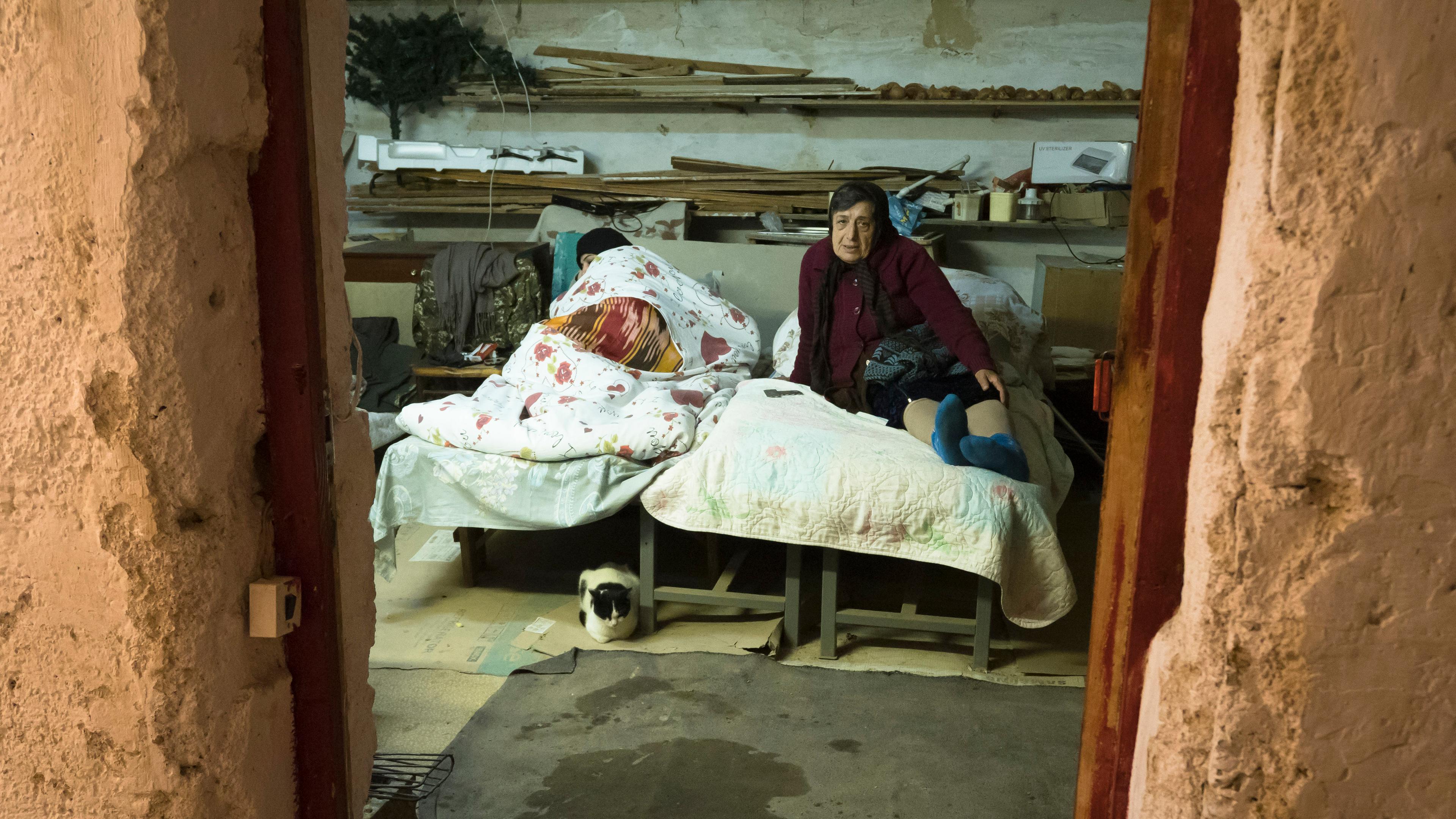 Frauen liegen in einem Bett in einem Schutzraum.