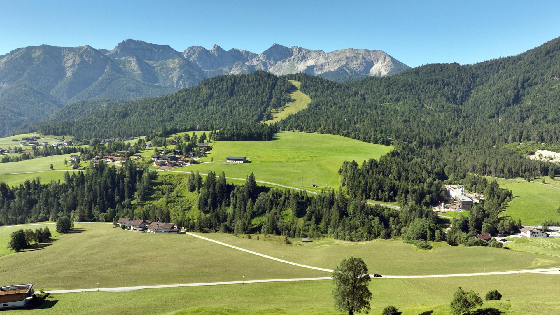 Panoramablick auf das Dorf Steinberg am Rofan, umgeben von üppigen grünen Wiesen und der majestätischen Bergkette des Rofans.
