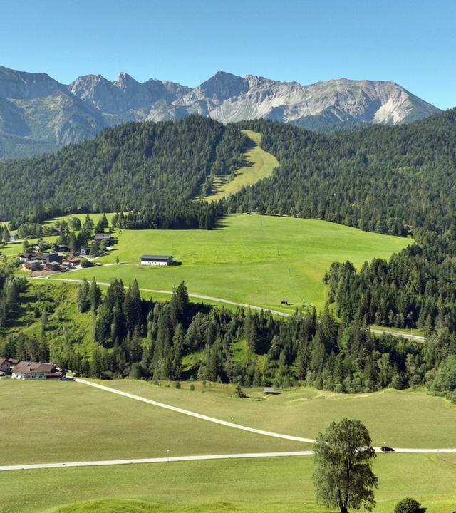 Panoramablick auf das Dorf Steinberg am Rofan, umgeben von üppigen grünen Wiesen und der majestätischen Bergkette des Rofans.
