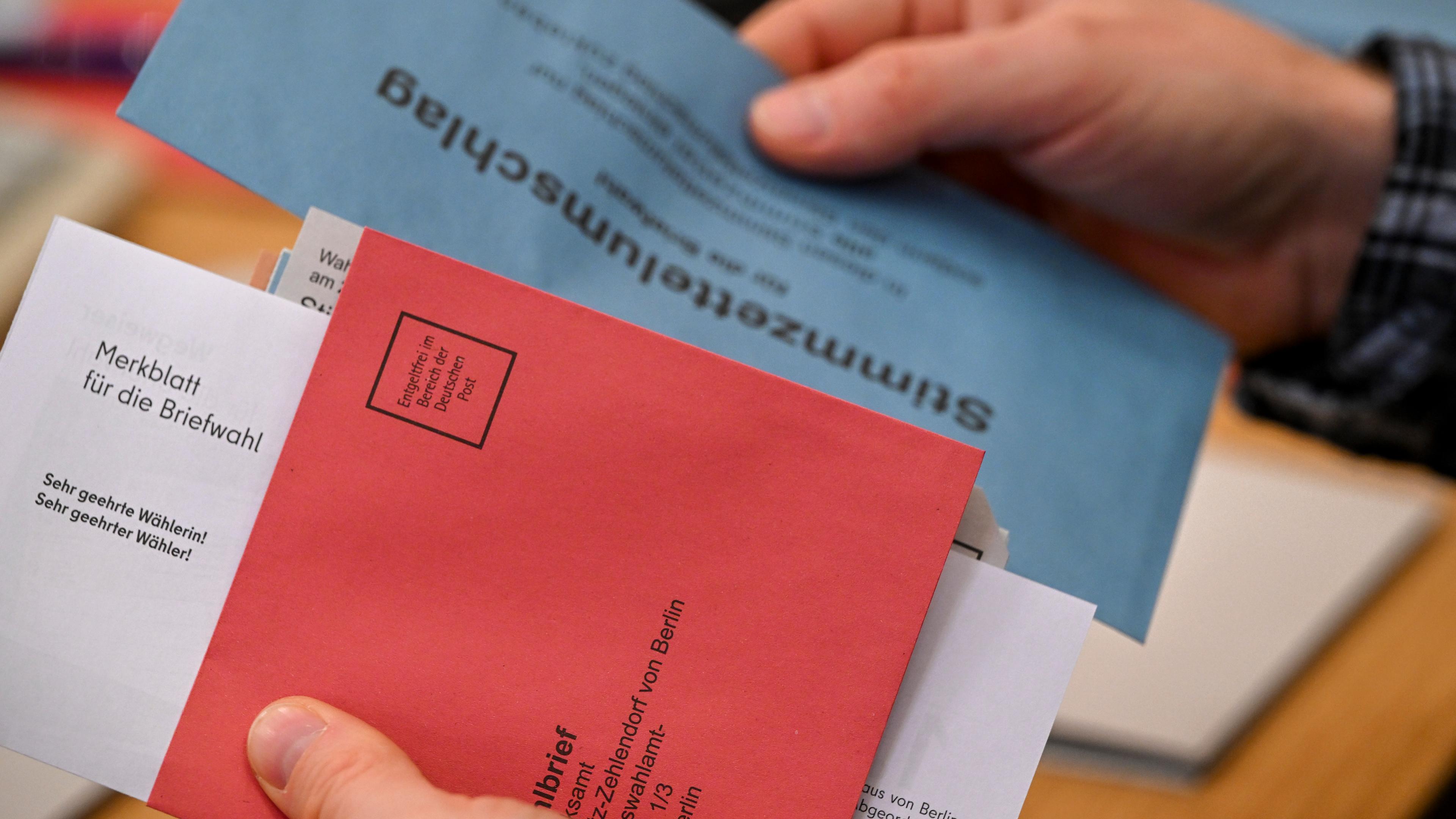 Das Bild zeigt eine Person, die Wahlunterlagen zur Briefwahl für die Wiederholungswahlen in Berlin in der Hand hält - die Wahlunterlagen wurden bei einem Pressetermin vorgestellt.
