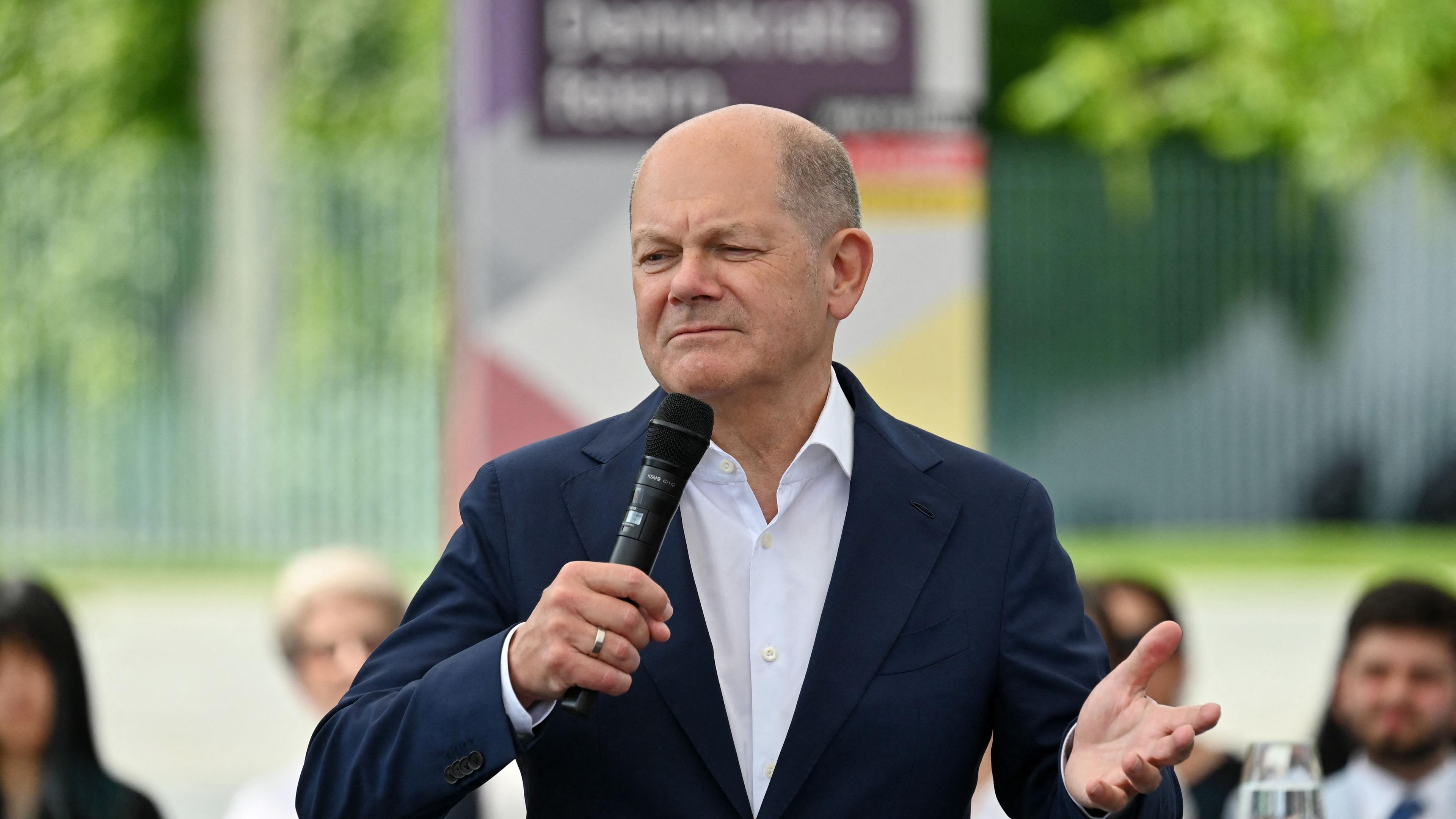 German Chancellor Olaf Scholz gestures as he speaks during a debate with citizens on the topic 'Together for Democracy' in front of the Chancellery and the Reichstag building (background) in Berlin, Germany on Mary 24, 2024,