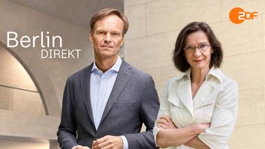 Wulf Schmiese und Diana Zimmermann stehen vor einem Regierugsgebäude in Berlin mit einer großen, runden Öffnung in der Außenmauer und blicken in die Kamera.
