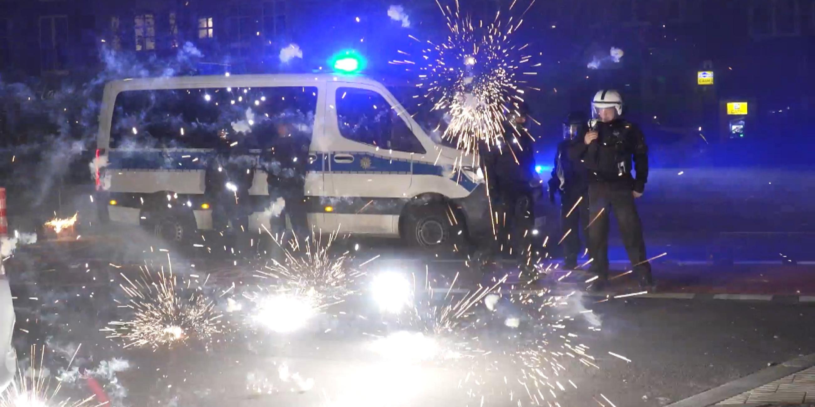 Berlin: Polizeibeamte stehen hinter explodierendem Feuerwerk.