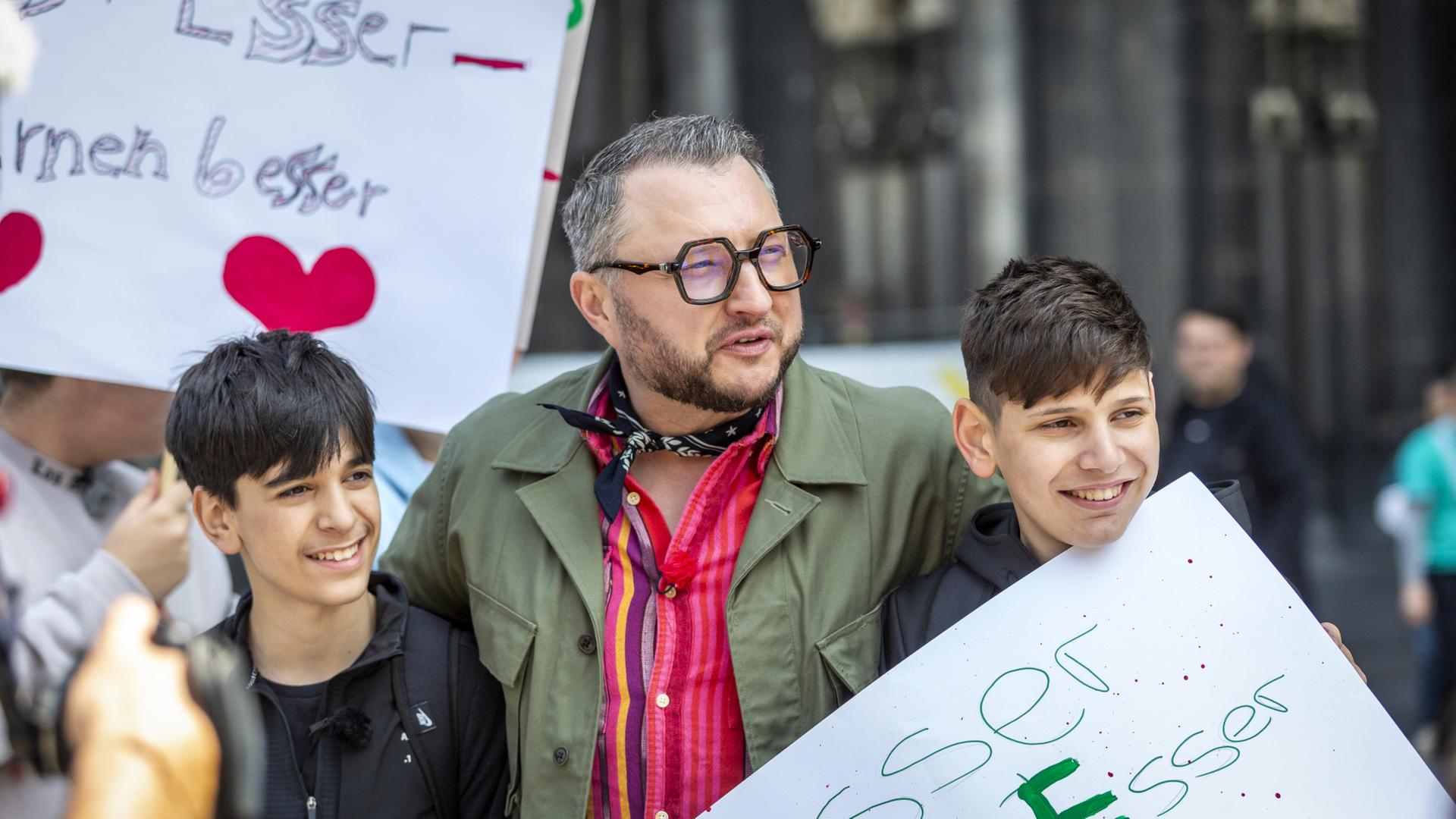 ZDFbesseresser Sebastian Lege mit zwei Schülern bei einer Unterschriftenaktion vor dem Kölner Dom