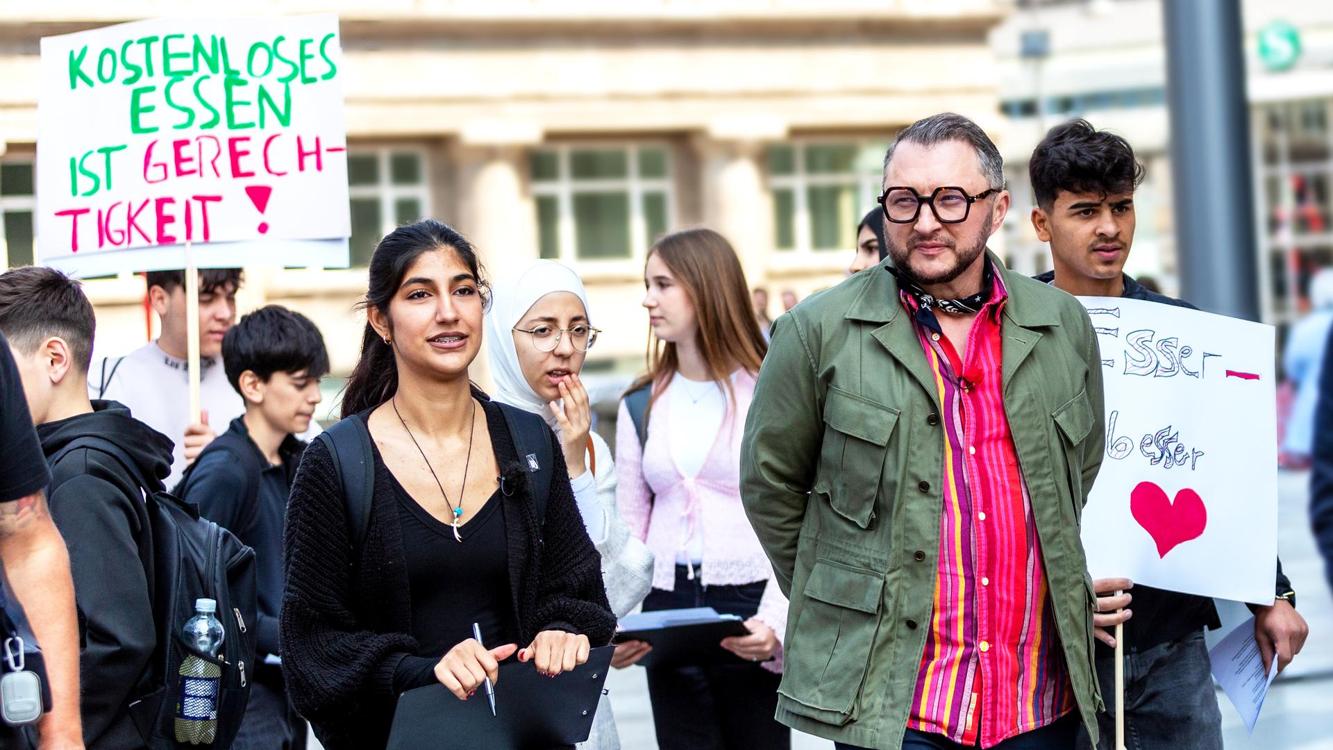 Sebastian Lege steht mit Schulkindern auf einer Demonstration für kostenloses Schulessen.
