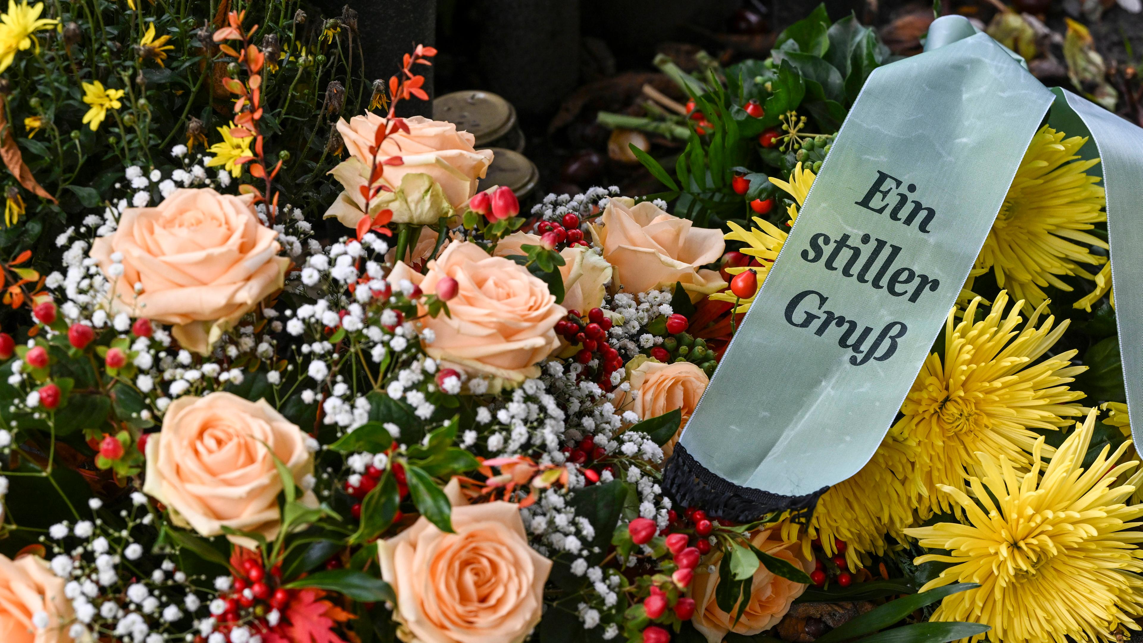 Viele Blumen in einem Strauß mit einem Trauerschleife mit der Aufschrift "Ein stiller Gruß".