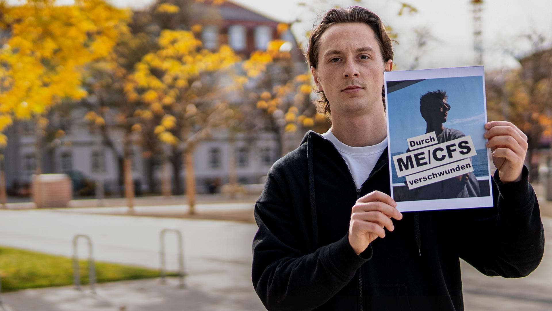 Jonas hält ein Bild von seinem besten Freund, Tom mit dem Schriftzug "Durch ME/CFS verschwunden" in der Hand und zeigt es in die Kamera