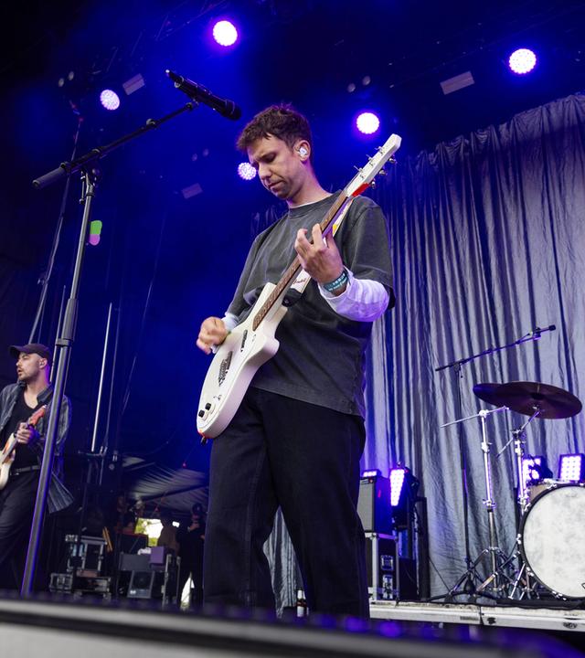 Zwei Musiker stehen auf einer Bühne und spielen Gitarre.