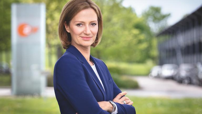 Bettina Schausten folgt auf Peter Frey als Chefredakteurin des ZDF. Das Foto zeigt Bettina Schausten im Außenbereich vor einem Schild mit einem ZDF-Logo.