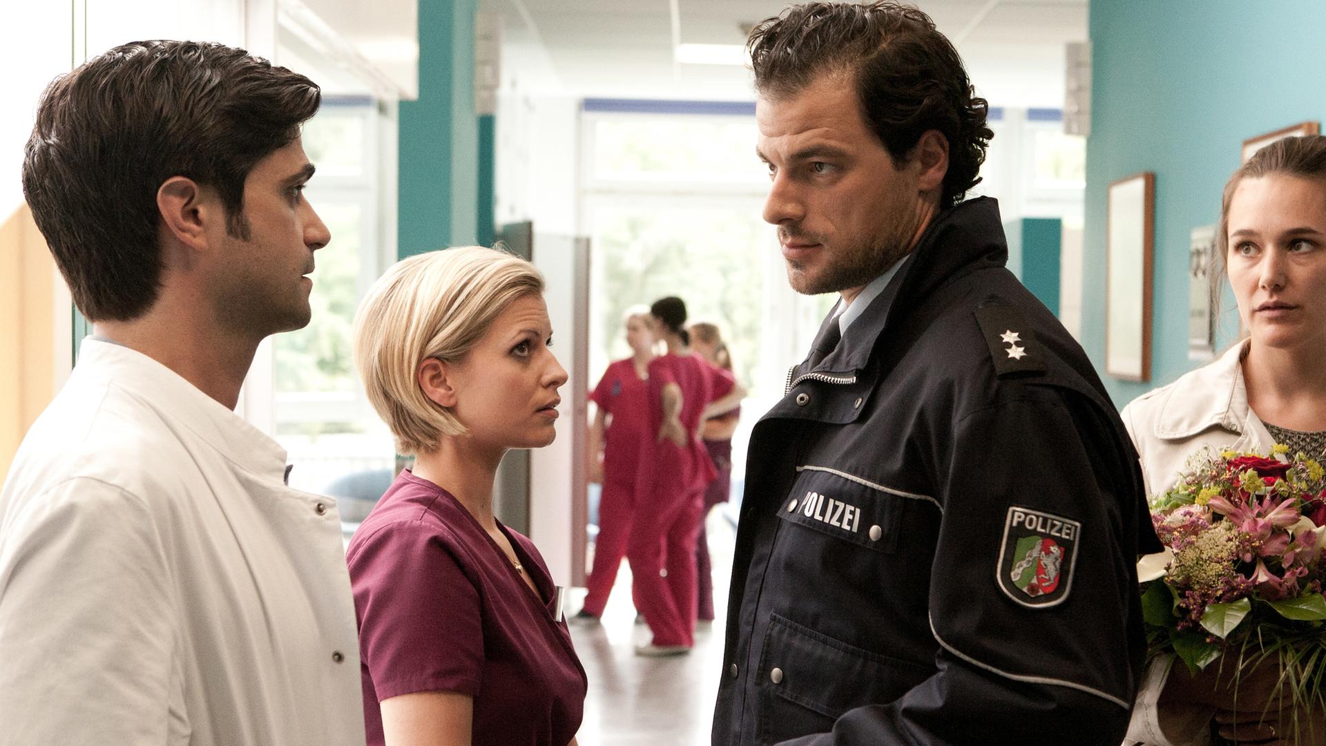  Dr. Behring (Maximilian Grill), Lizzy (Theresa Underberg), Thomas Müller (Tobias Licht) und seine Frau Daniela (Alissa Jung) im Flur der Klinik