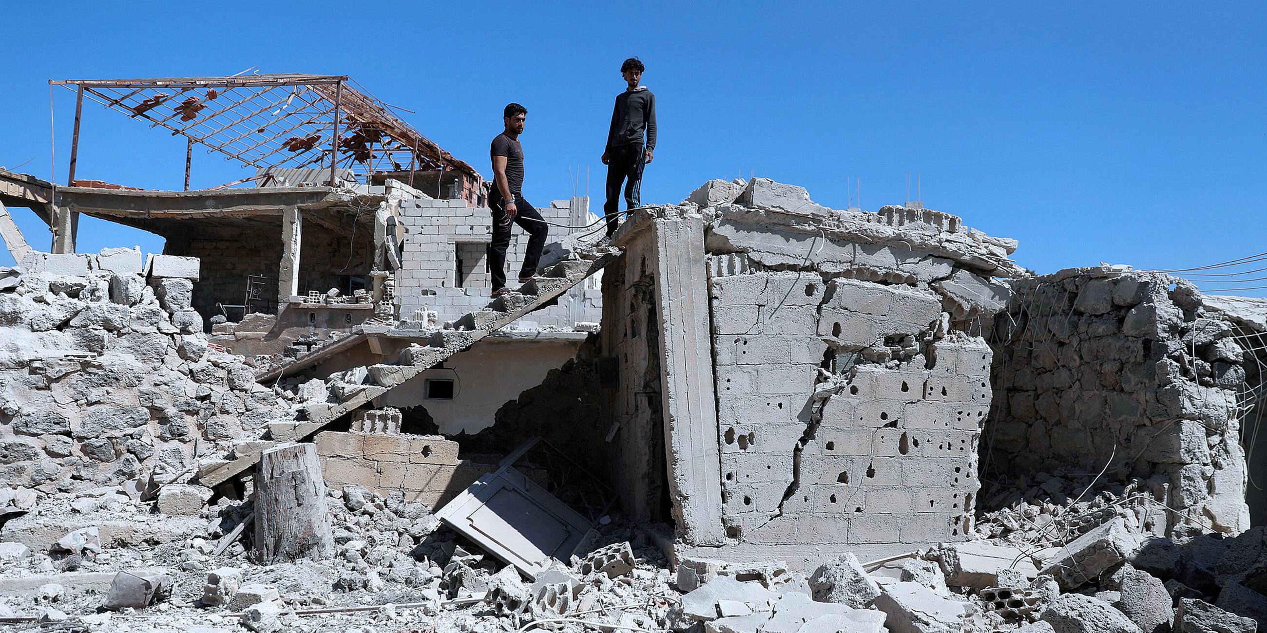 Archiv: Männer inspizieren ein zerstörtes Gebäude in Syrien
