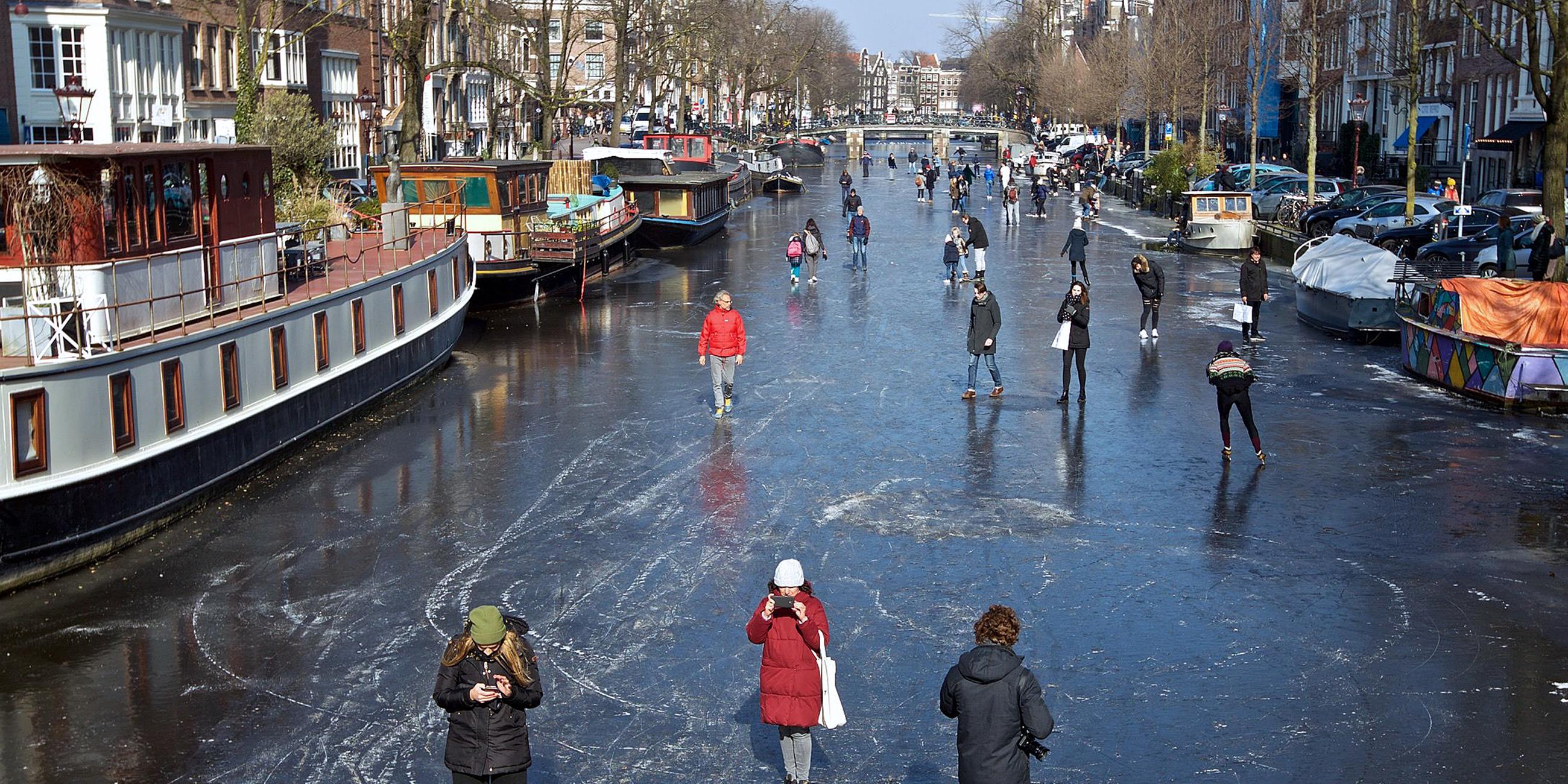 Menschen gehen auf der zugefrorenen Prinsengracht in Amsterdam, aufgenommen am 02.03.2018