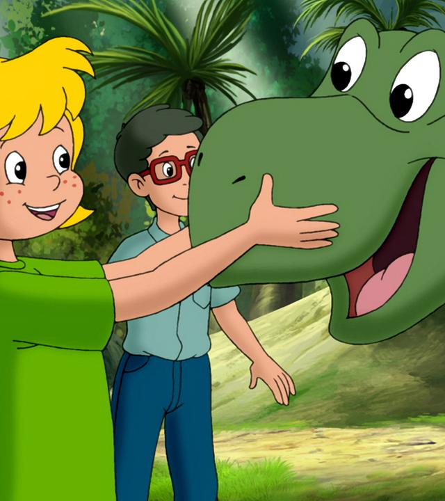 Bibi und Florian streicheln einen jungen grünen Dinosaurier.