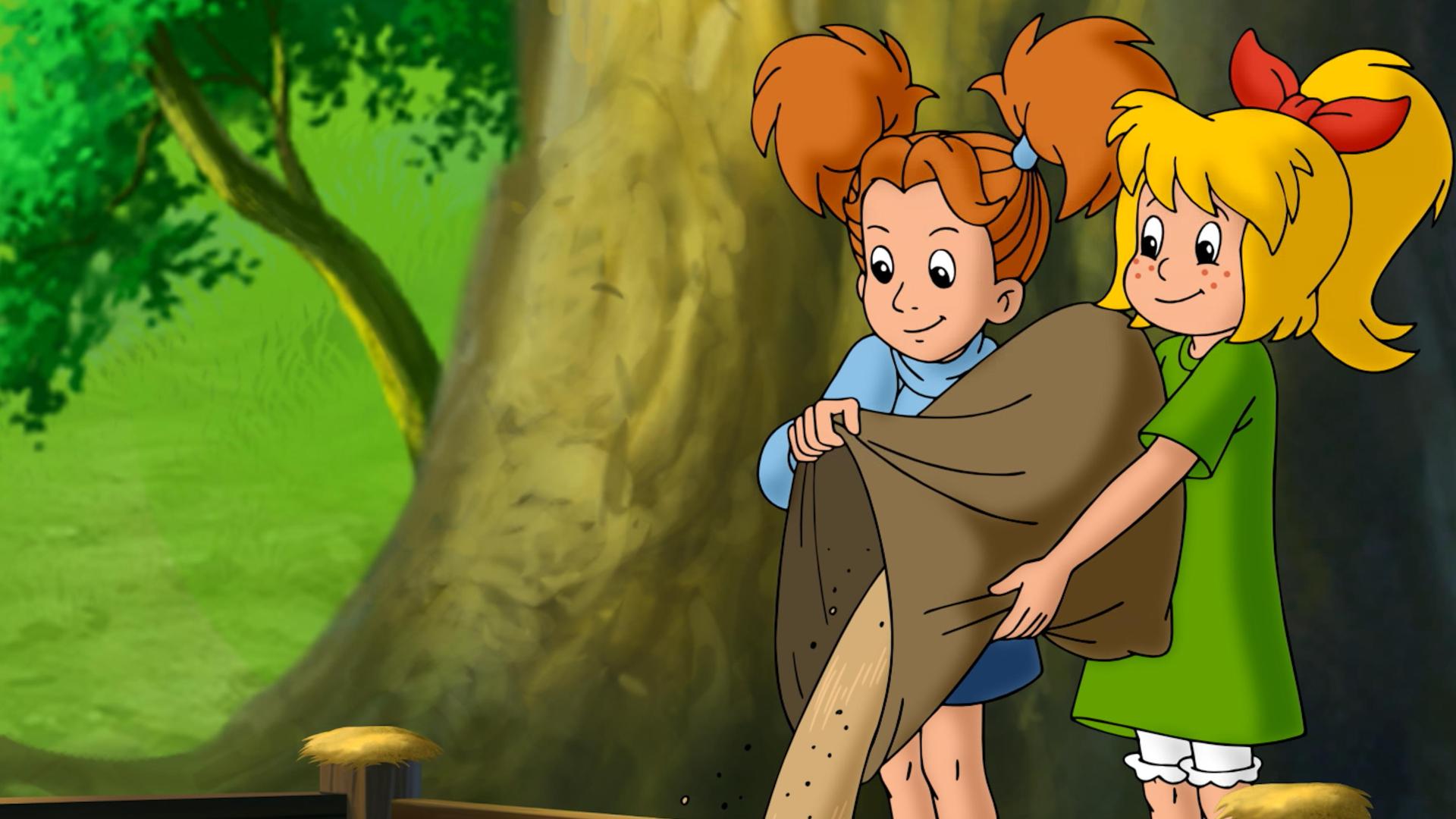 Bibi und Marita stehen nebeneinander und schütten gemeinsam einen Sack Sand in eine Holzumrandung mitten im Wald.