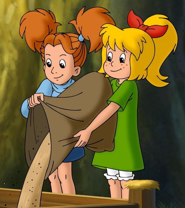 Bibi und Marita stehen nebeneinander und schütten gemeinsam einen Sack Sand in eine Holzumrandung mitten im Wald.