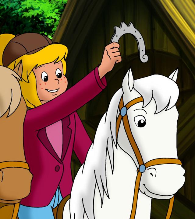 Bibi hält neben Tina das gefundene Hufeisen hoch.