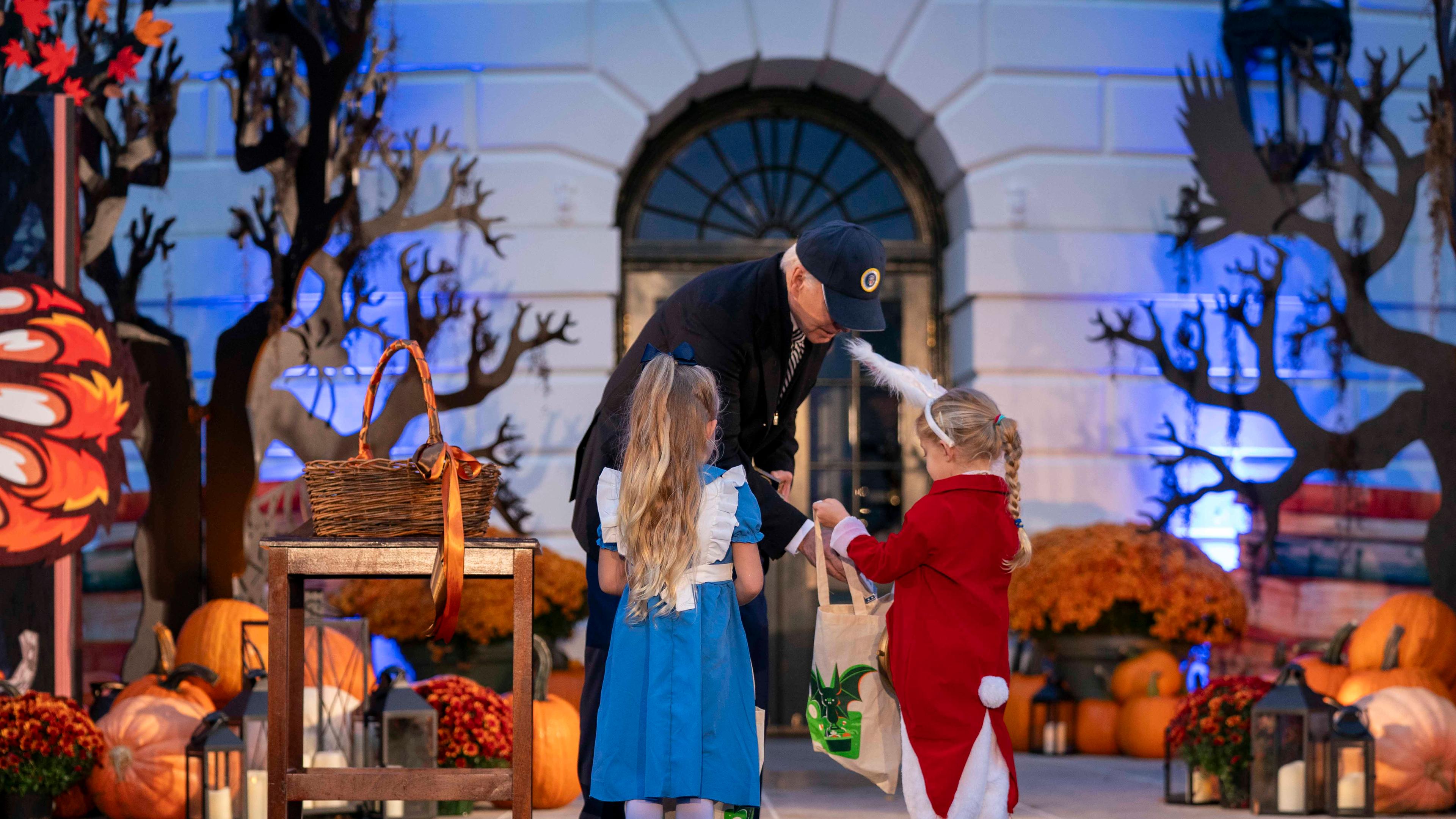 Joe Biden gibt zwei kleinen Mädchen in Kostümen Süßigkeiten.