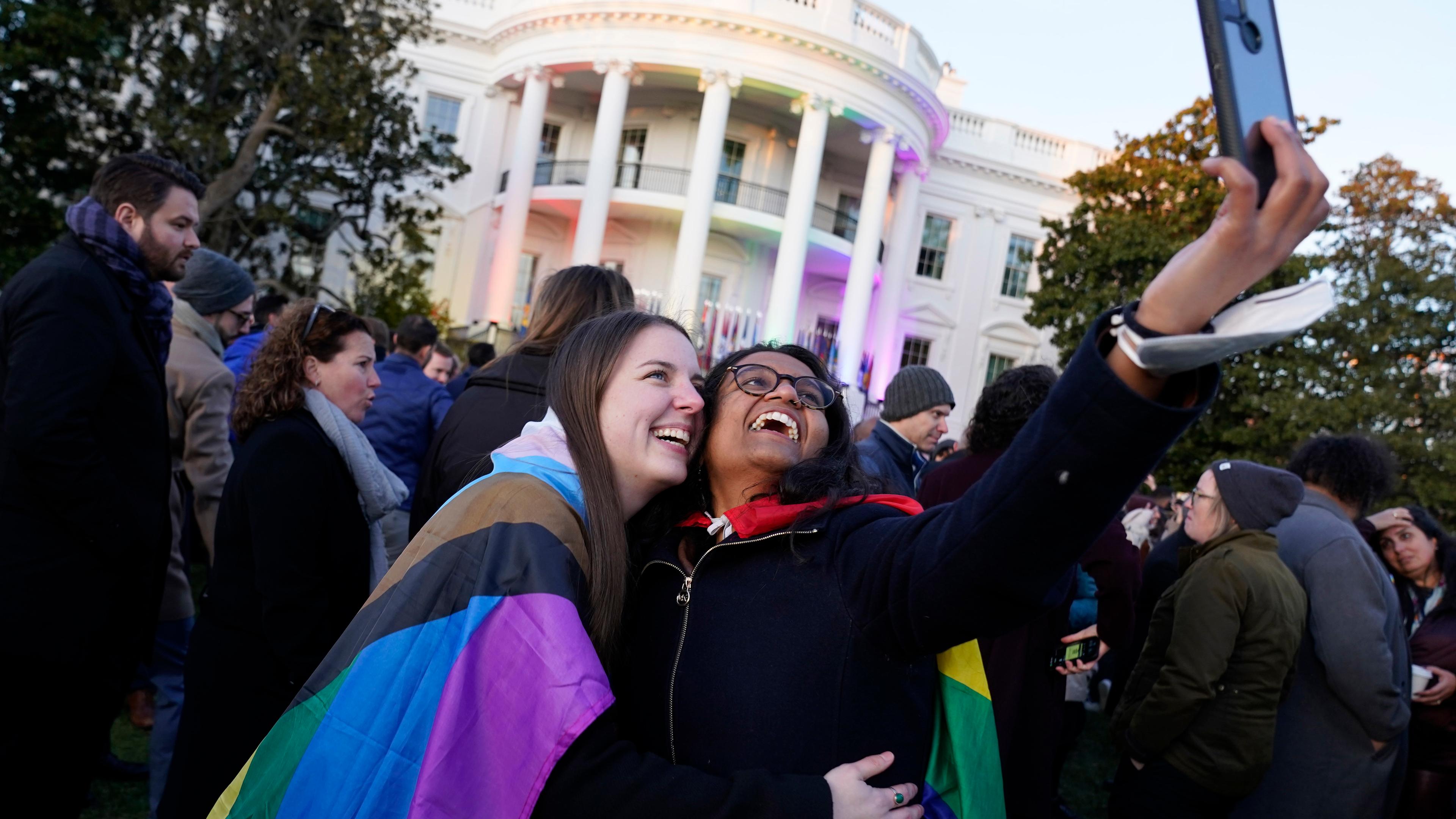Zwei in die Pride-Fahne gehüllte Frauen vor dem Weißen Haus. 