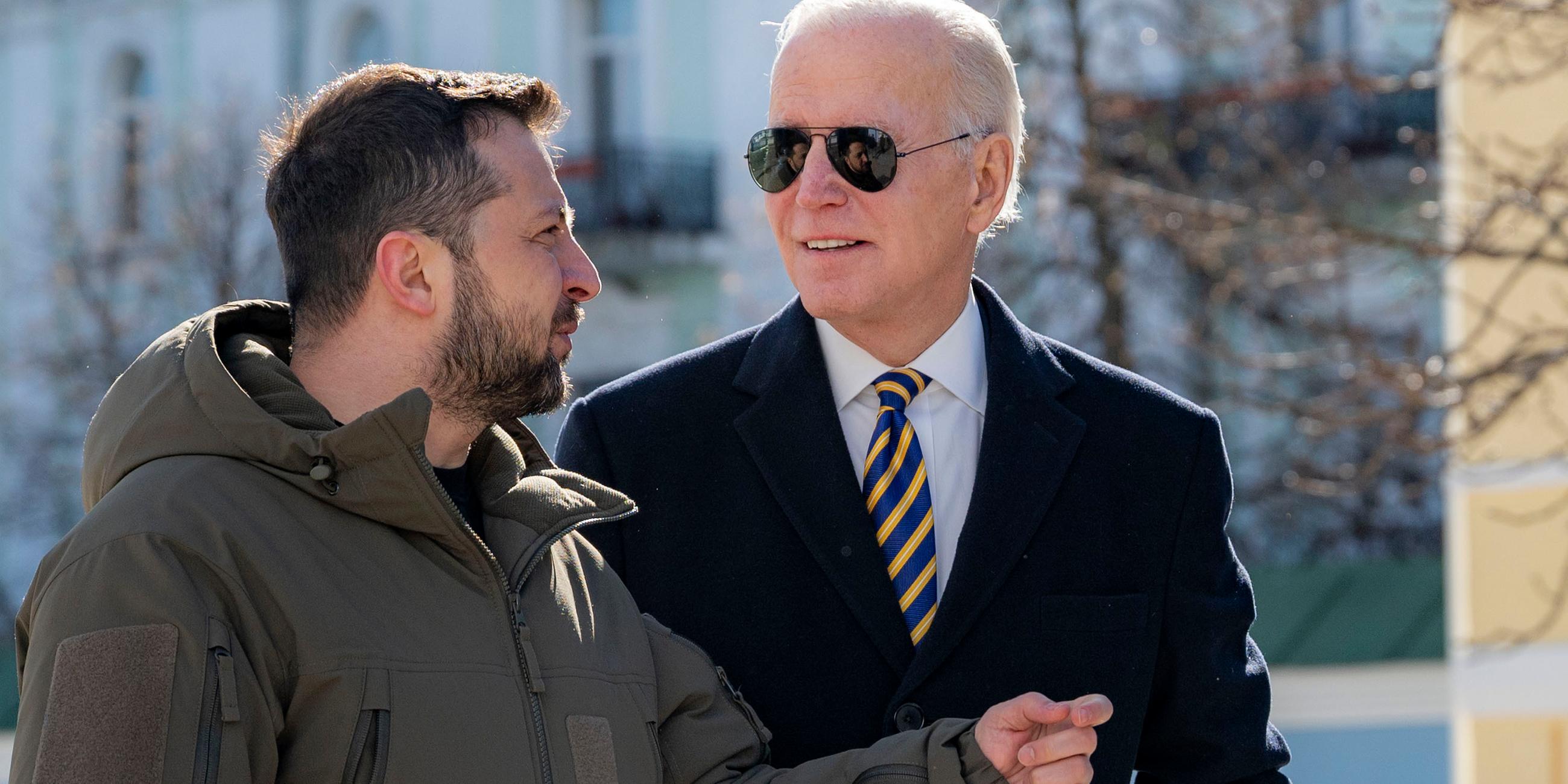 Joe Biden (r), Präsident der USA, und Wolodymyr Selenskyj, Präsident der Ukraine, unterhalten sich auf offener Straße.