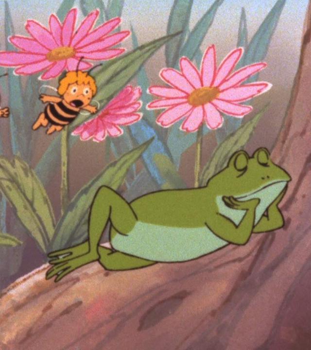 Ein großer, grüner Frosch schläft auf einem Baumstamm neben der Blumenwiese. Die zwei kleinen Bienen Willi und Maja nähern sich ihm im Flug.