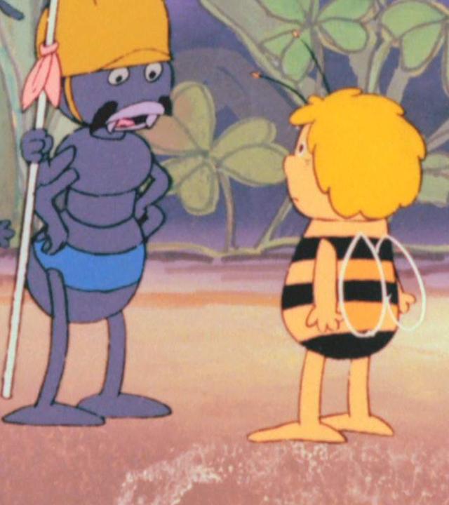Links stehen drei Ameisen mit Helm. Die erste trägt zusätzlich eine Lanze. Rechts daneben steht Maja, ein kleines Bienenmädchen. Im Hintergrund wachsen Gräser, Klee und Blumen.