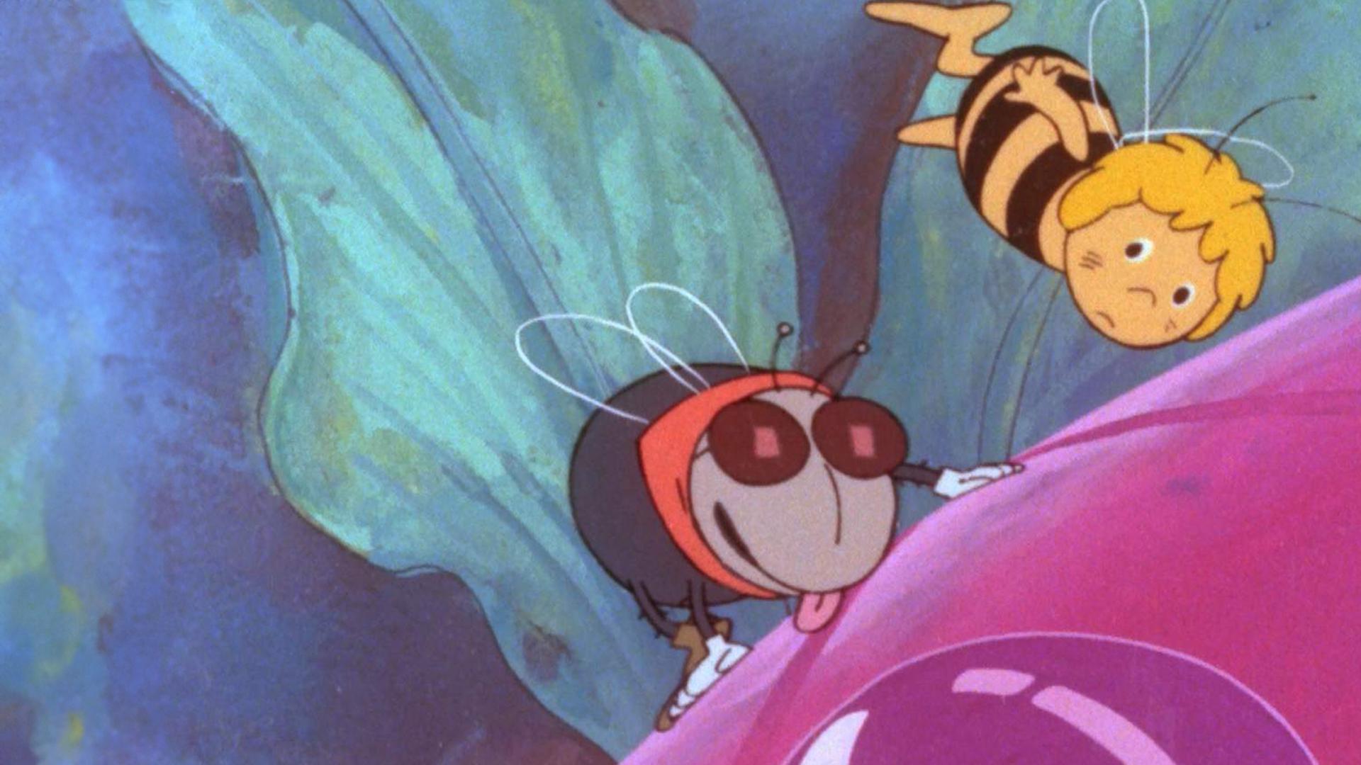 Auf einer roten Blüte sitzt Stubenfliege Puck mit Brille. Rechts über ihr fliegt Maja, das kleine Bienenmädchen.