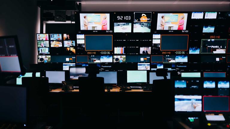 Dunkler Regieraum der ZDF-Regie mit in der Dunkelheit leuchtenden Bildschirmen.