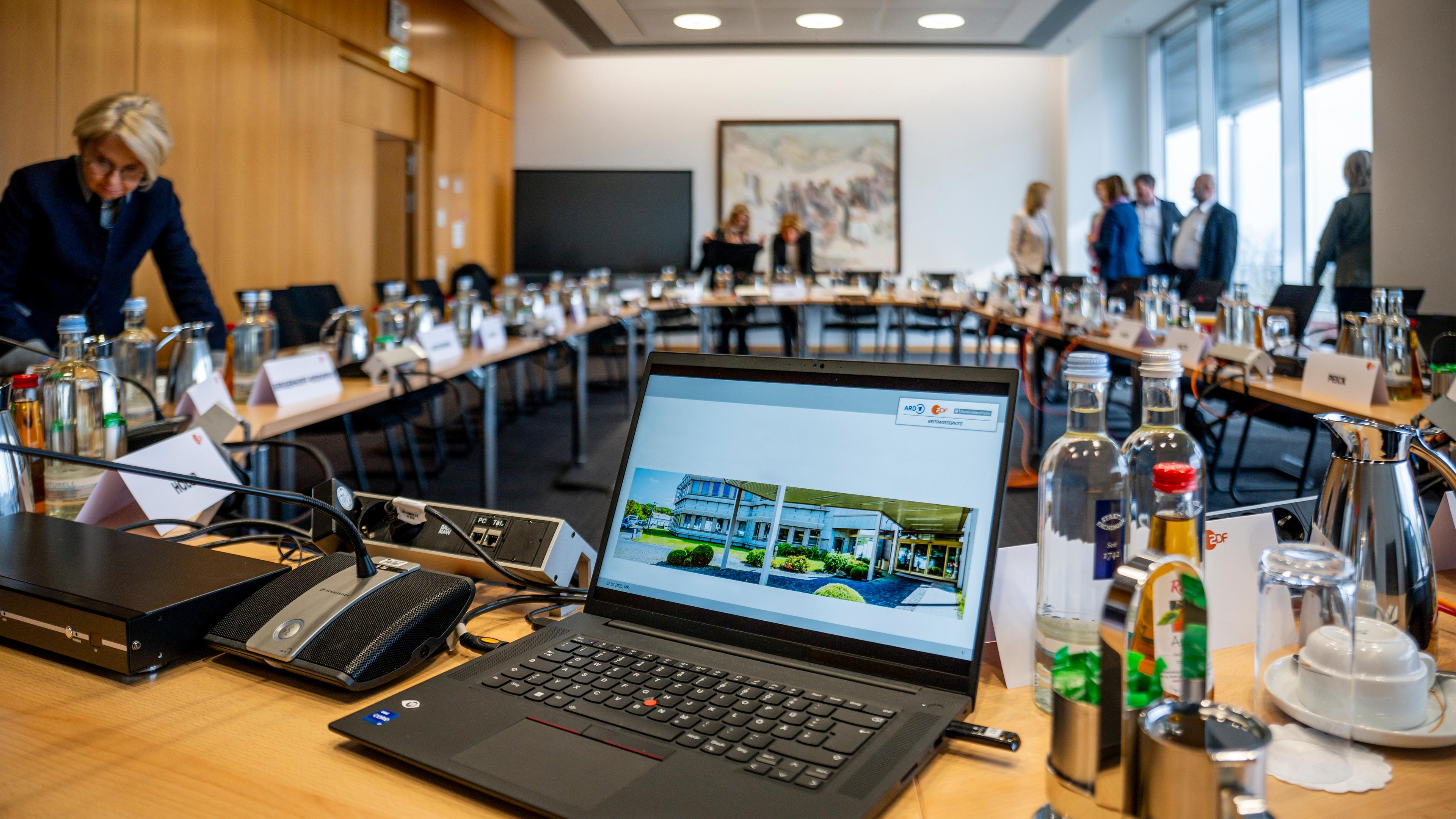 Typicals für die ZDF-Verwaltungsratssitzung: Laptop in einem Konferenzraum mit Menschen verschwommen im Hintergrund