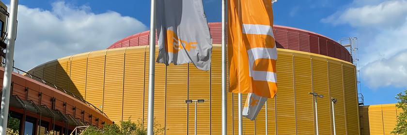 Zwei ZDF-Fahnen in Silber und ZDF-Orange vor dem ZDF-Sendebetriebsgebäude