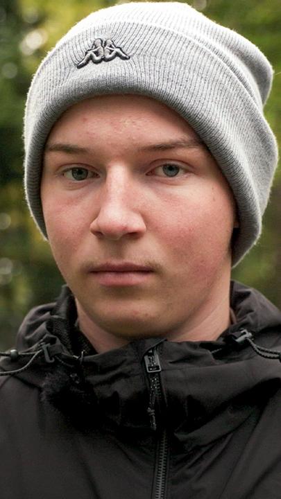 Teenager steht auf dem Friedhof am Grab seiner Eltern