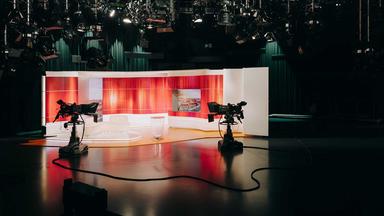 Leeres ZDF-Fernsehstudio mit dunklem Vordergrund und roter Hintergrunddekoration hinter Sitzgruppe