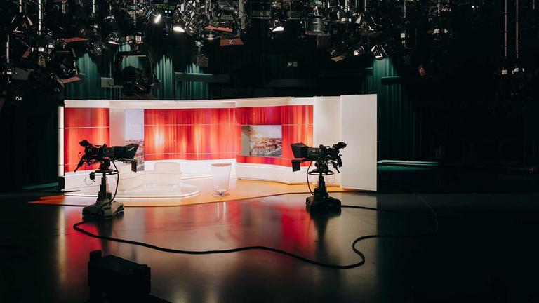 Leeres ZDF-Fernsehstudio mit dunklem Vordergrund und roter Hintergrunddekoration hinter Sitzgruppe